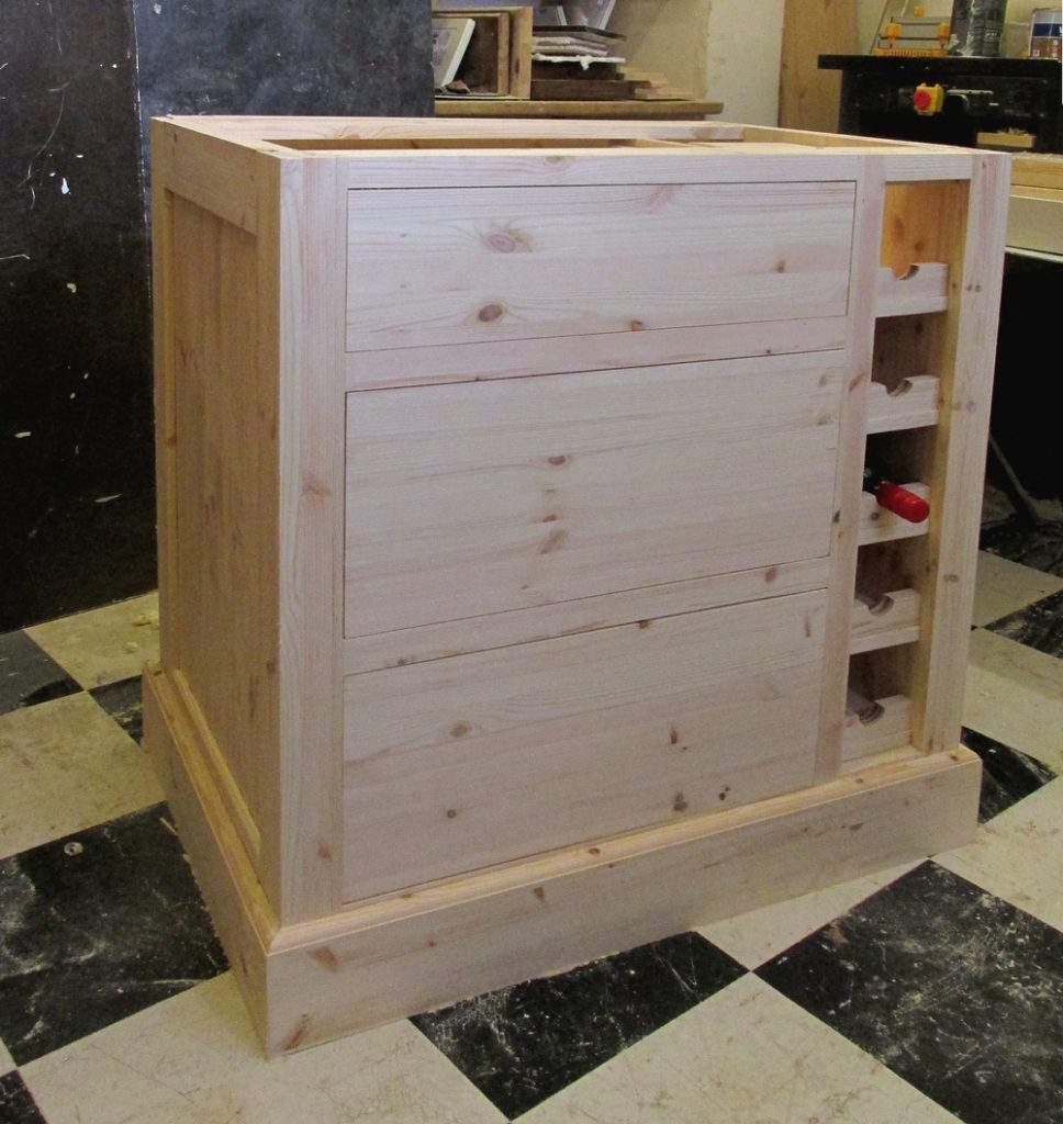 a kitchen island in unpainted pine with drawers and a wine rack